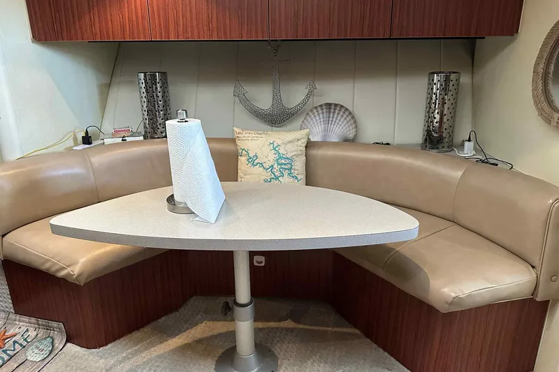 Slide: The Image of 1993 Mainship 39 Express interior with beige seating, table, and nautical decor. - 6