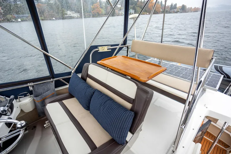 Slide: The Image of 2016 Cutwater 30 CB boat interior with cushioned seating and wooden table on a lake. - 15
