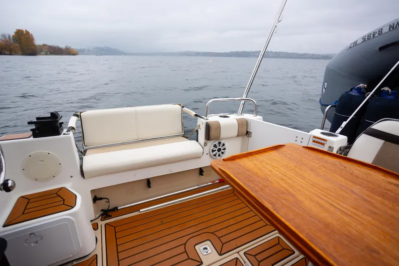 Slide: The Image of 2016 Cutwater 30 CB boat interior with wooden deck and seating, overlooking a calm lake. - 18