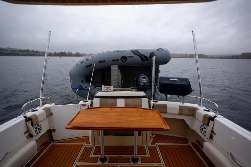 Slide: The Image of 2016 Cutwater 30 CB boat interior with wooden table and inflatable dinghy on water. - 19