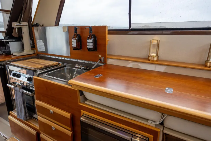 Slide: The Image of Interior of 2016 Cutwater 30 CB boat featuring a compact kitchen with wooden cabinetry. - 5