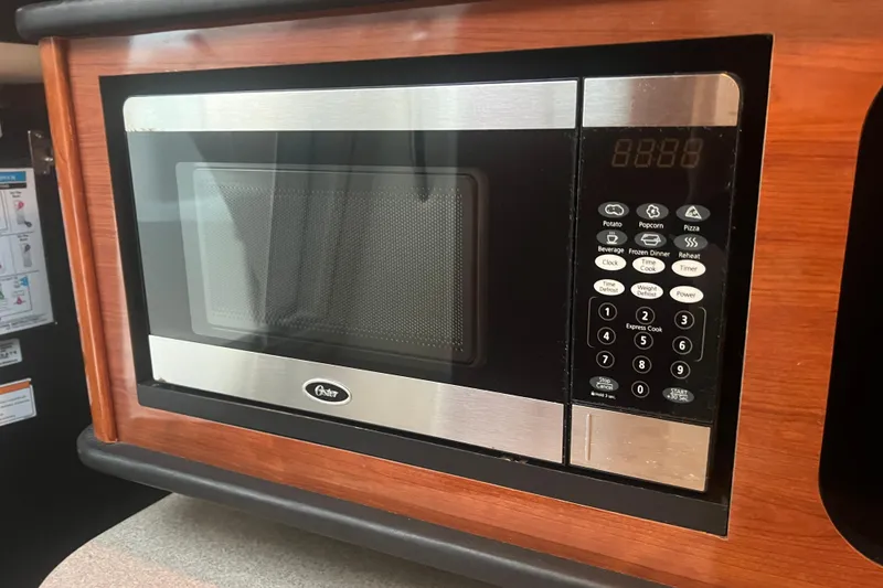 Slide: The Image of Microwave oven inside 2007 Sea Ray 260 Sundancer boat, featuring digital controls and wood paneling. - 11