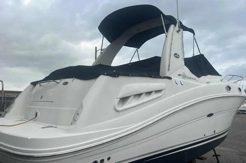 Slide: The Image of 2007 Sea Ray 260 Sundancer boat with black canopy, docked under cloudy skies. - 47