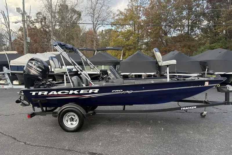 Slide: The Image of 2019 Tracker Pro 170 boat on trailer, parked outdoors with covered boats in background. - 17