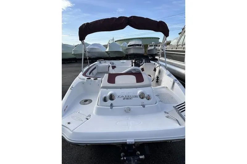 Slide: The Image of 2018 Tahoe 215 Xi boat with maroon canopy, docked outdoors. - 11