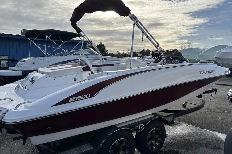 Slide: The Image of 2018 Tahoe 215 Xi boat on trailer, parked outdoors under cloudy sky. - 13