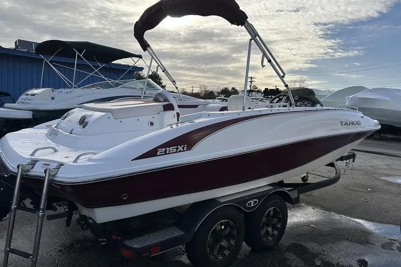 Slide: The Image of 2018 Tahoe 215 Xi boat on trailer, white and maroon, parked outdoors. - 15