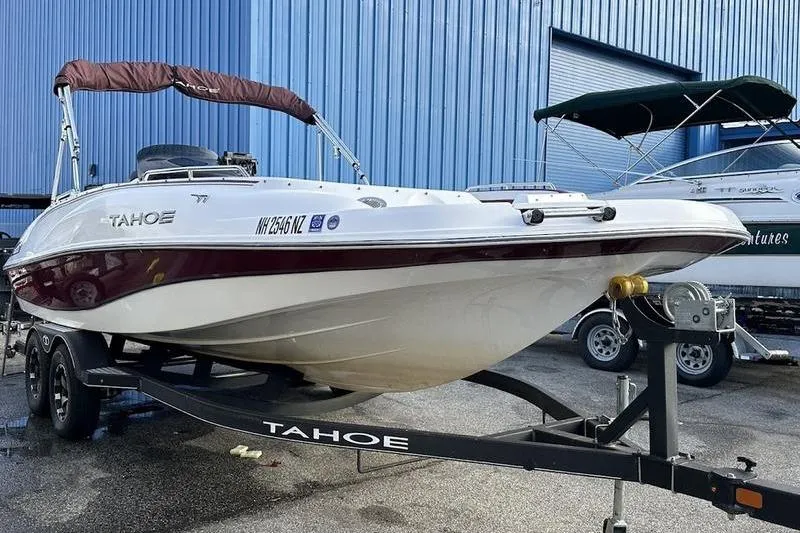 Slide: The Image of 2018 Tahoe 215 Xi boat on trailer, parked near blue building. - 4