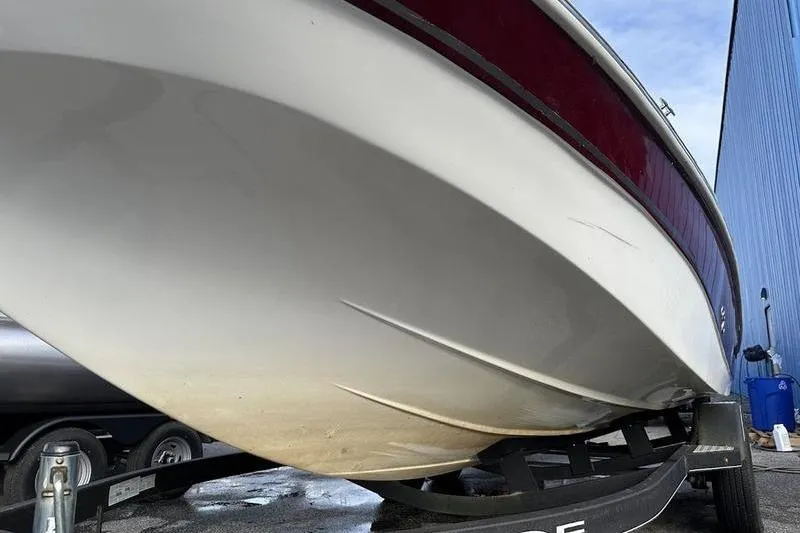 Slide: The Image of 2018 Tahoe 215 Xi boat on trailer, viewed from below, near blue building. - 5