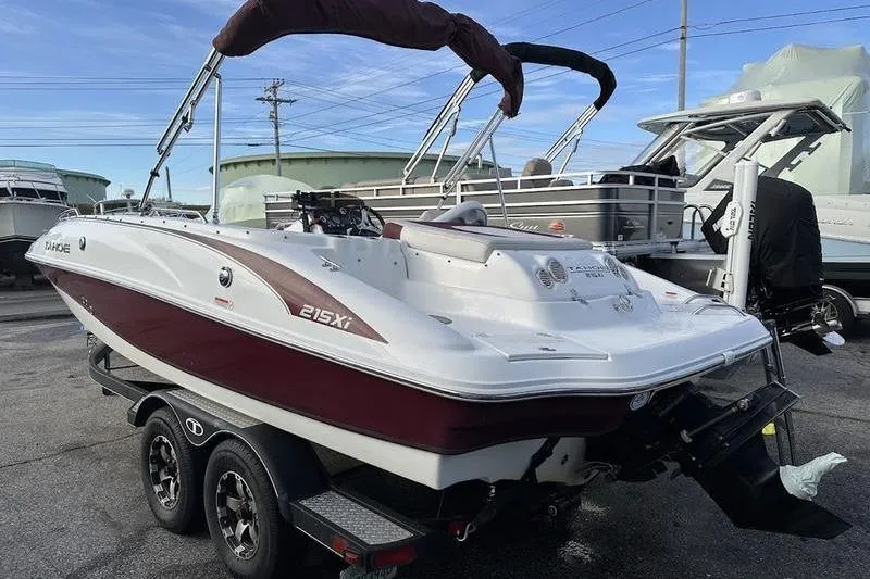 Slide: The Image of 2018 Tahoe 215 Xi boat on trailer, parked outdoors, with bimini top. - 6