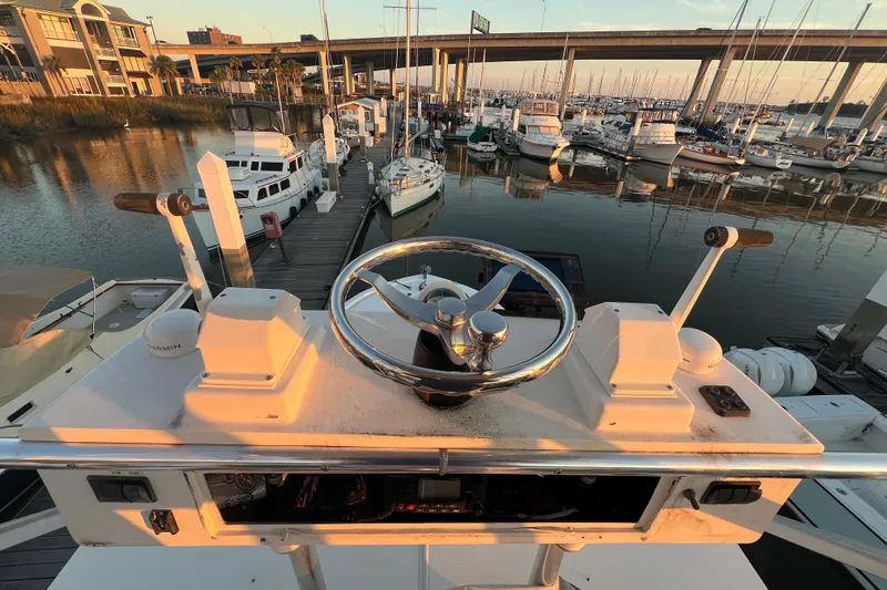 Slide: The Image of Helm of 2002 Out Island 38 Express Fisherman at marina, overlooking docked boats and bridge. - 12