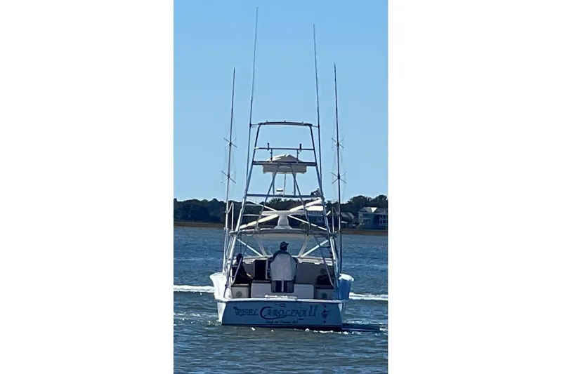 Slide: The Image of 2002 Out Island 38 Express Fisherman boat on water, rear view, clear sky. - 6