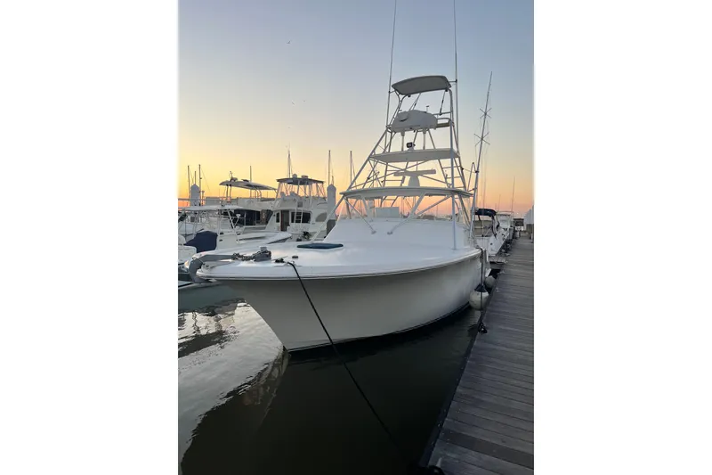 Slide: The Image of 2002 Out Island 38 Express Fisherman docked at sunset, showcasing sleek design and fishing tower. - 9