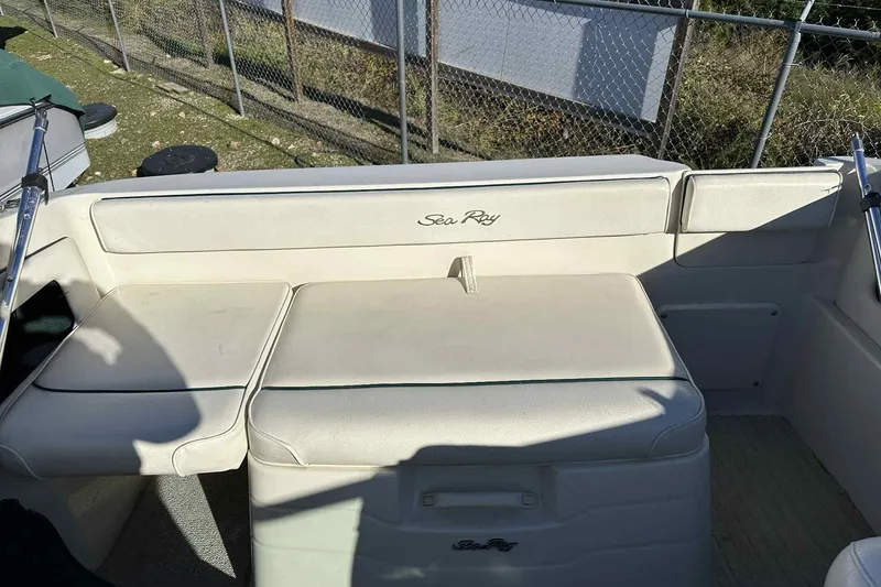 Slide: The Image of 2000 Sea Ray 215 Express Cruiser interior seating with white upholstery and logo. - 7