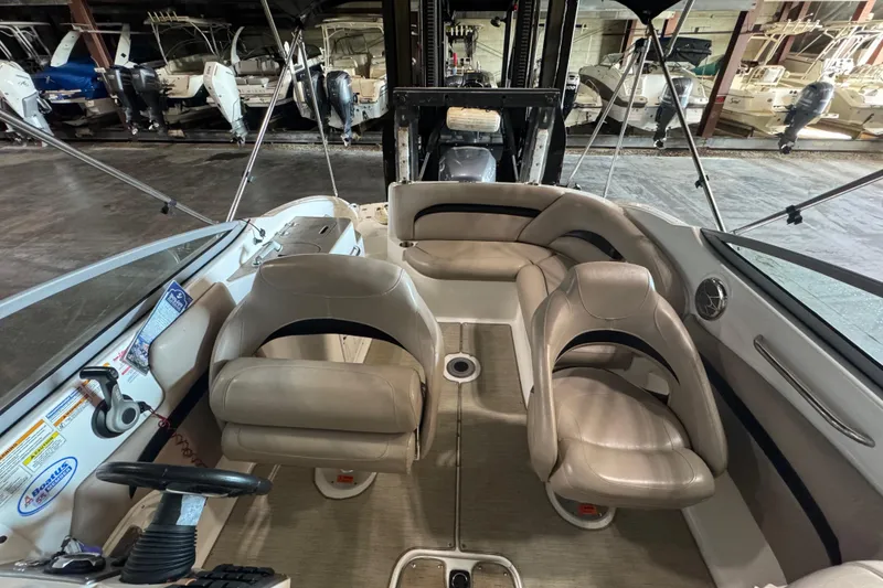 Slide: The Image of 2014 Hurricane SunDeck 2400 OB interior with beige seating and steering wheel in a showroom. - 14