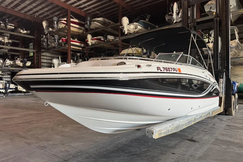 Slide: The Image of 2014 Hurricane SunDeck 2400 OB boat in storage, featuring sleek black and white design. - 3