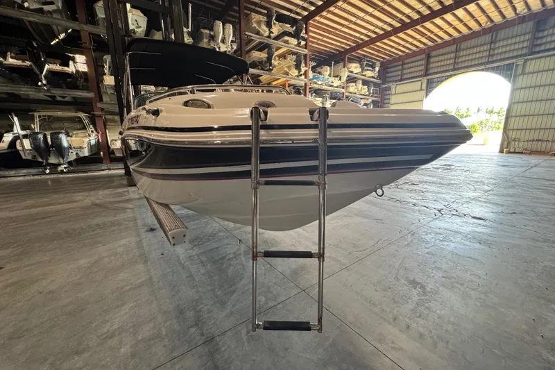 Slide: The Image of 2014 Hurricane SunDeck 2400 OB boat in storage with ladder, indoor warehouse setting. - 6