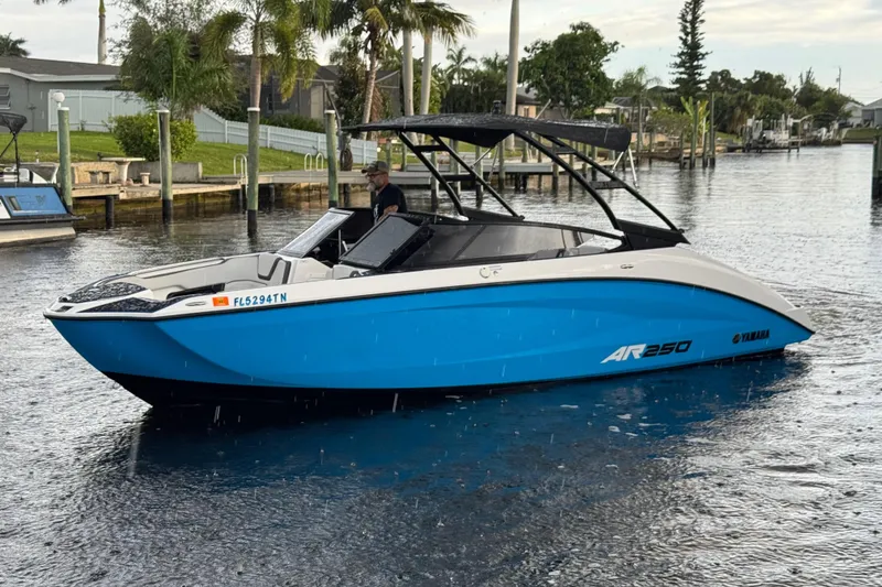 The Image of 2023 Yamaha Boats AR250 in blue, cruising on a calm waterway. - 1