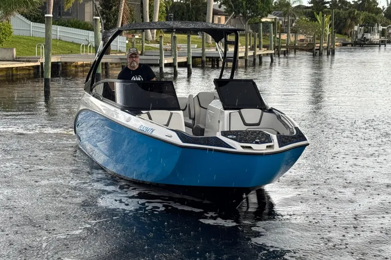 Slide: The Image of 2023 Yamaha Boats AR250 in water, blue and white design, dockside view. - 3