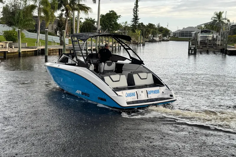 Slide: The Image of 2023 Yamaha Boats AR250 cruising on a scenic waterway, surrounded by lush greenery. - 6
