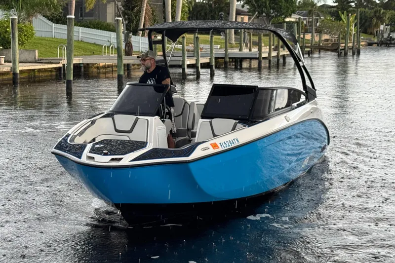 Slide: The Image of 2023 Yamaha Boats AR250 in water, blue hull, sleek design, under cloudy sky. - 9