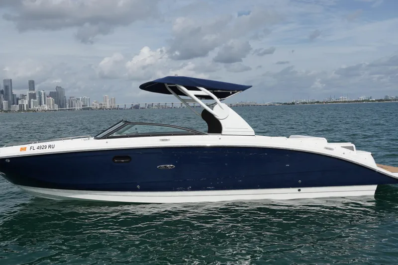 Slide: The Image of 2018 Sea Ray SDX 290 boat on water with city skyline in background. - 2
