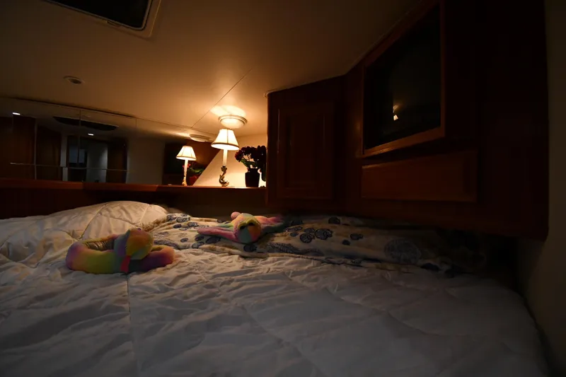 Slide: The Image of Cozy bedroom interior of 1996 Viking 50 Convertible yacht with soft lighting and plush bedding. - 28