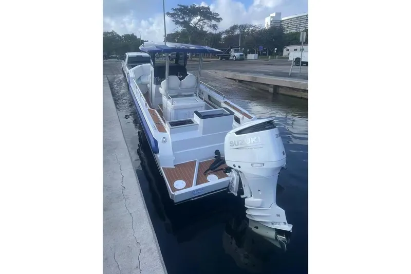 Slide: The Image of 2025 Norseman C280 Center Console boat with Suzuki outboard engine docked by the water. - 5