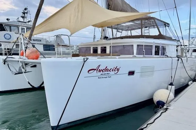 The Image of 2013 Lagoon 450 catamaran sailing on water with white sails and spacious deck. - 0