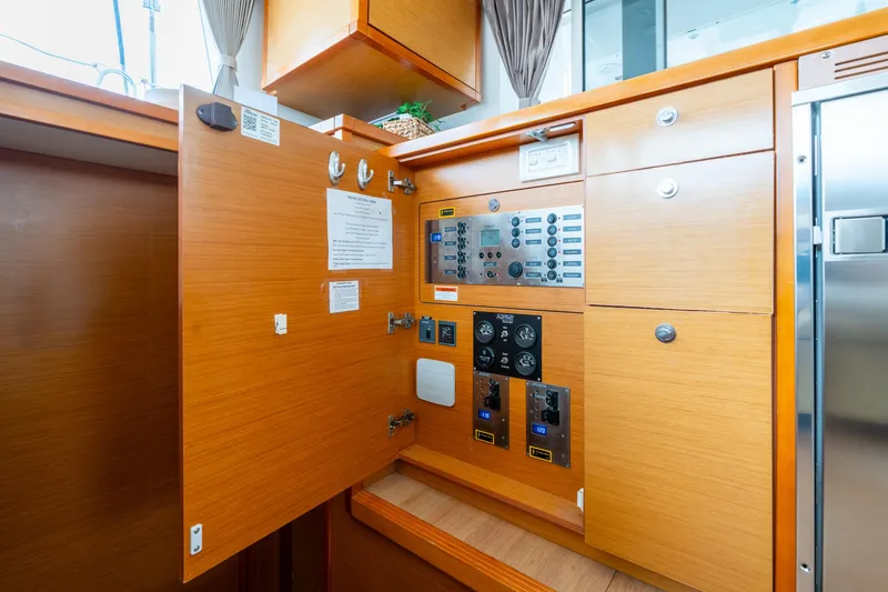 Slide: The Image of Electrical panel inside 2013 Lagoon 450 yacht with wooden cabinetry and control gauges. - 140
