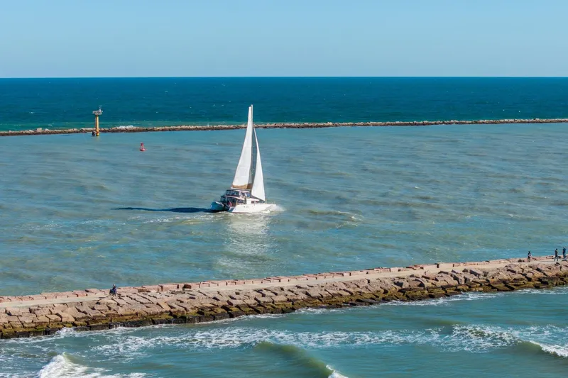 Slide: The Image of Sailboat Lagoon 450 (2013) navigating near a rocky pier on a sunny day. - 152