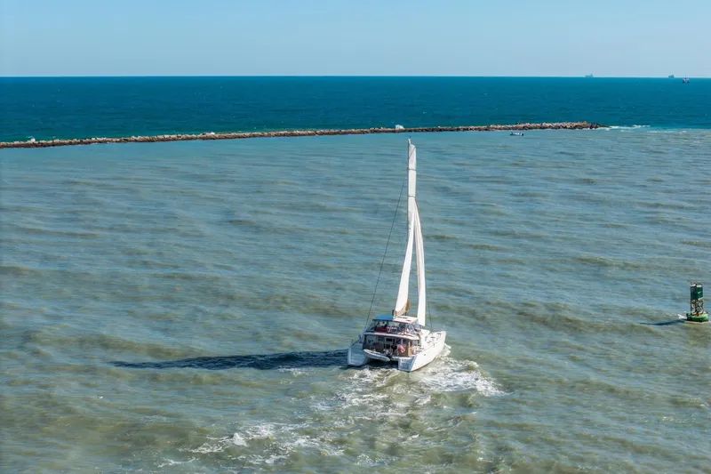 Slide: The Image of Sailing catamaran Lagoon 450, 2013 model, navigating open sea near breakwater. - 153