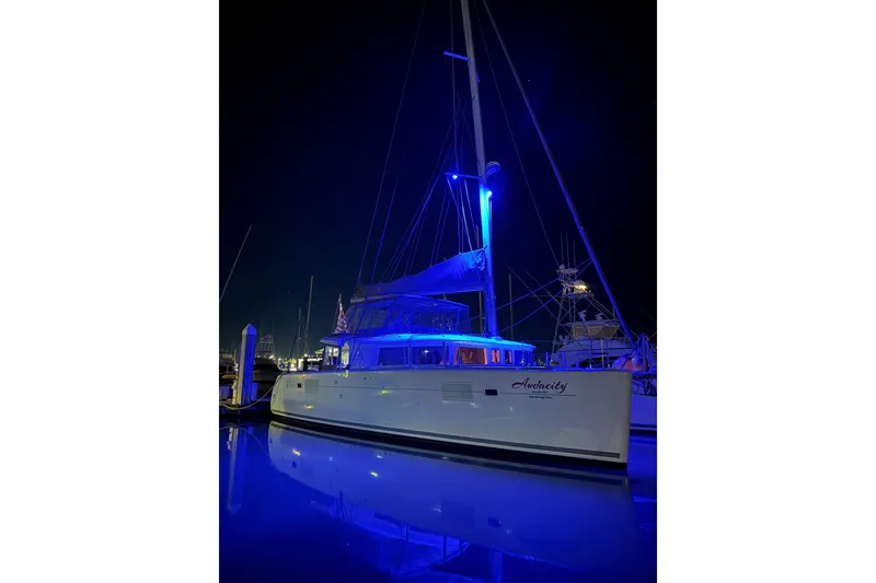 Slide: The Image of 2013 Lagoon 450 catamaran sailing on sunlit water, showcasing elegant design and spacious deck. - 2