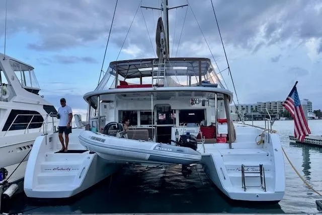 Slide: The Image of 2013 Lagoon 450 catamaran sailing in clear blue waters near a sandy shoreline. - 4