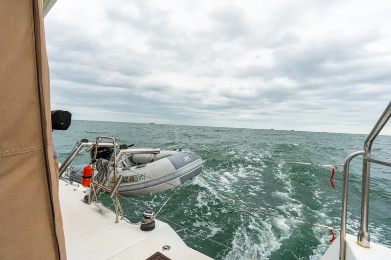 Slide: The Image of Sailing on a 2013 Lagoon 450 catamaran with a dinghy, ocean view, and cloudy sky. - 46