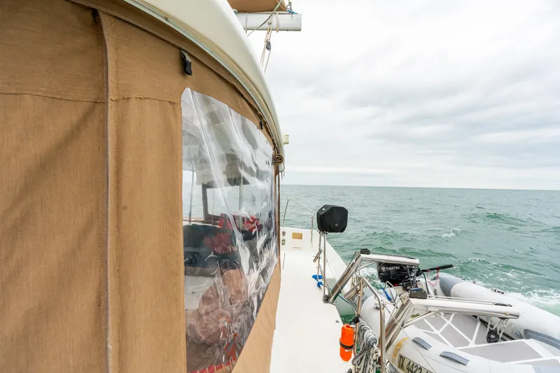 Slide: The Image of 2013 Lagoon 450 catamaran sailing on open sea with dinghy attached. - 47