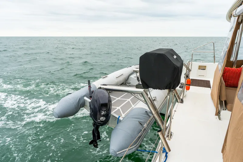 Slide: The Image of 2013 Lagoon 450 yacht with inflatable dinghy and outboard motor on open sea. - 51