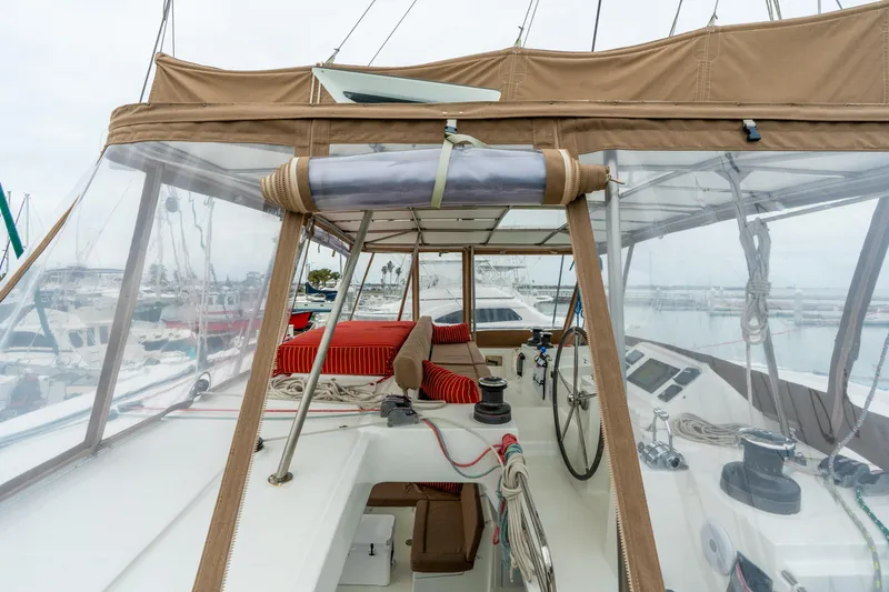 Slide: The Image of 2013 Lagoon 450 catamaran cockpit with red cushions and clear canopy in marina setting. - 74