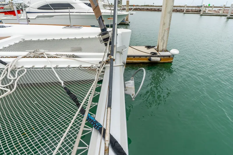 Slide: The Image of 2013 Lagoon 450 catamaran docked, featuring netting and mooring lines. - 76