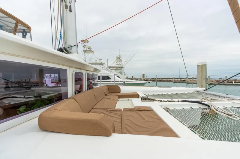 Slide: The Image of 2013 Lagoon 450 catamaran with brown seating, docked at a marina under cloudy skies. - 78