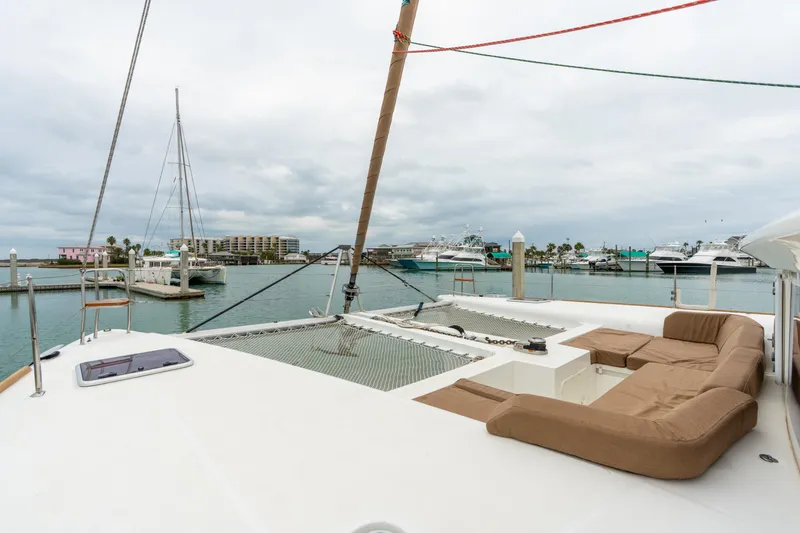 Slide: The Image of 2013 Lagoon 450 catamaran with spacious deck and seating in a marina setting. - 81