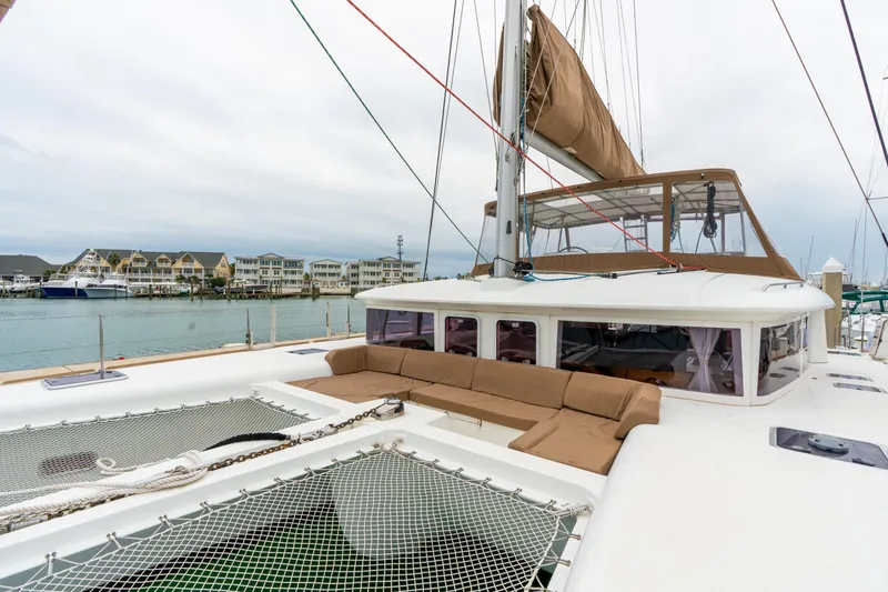 Slide: The Image of 2013 Lagoon 450 catamaran with spacious deck and seating, docked near waterfront homes. - 82