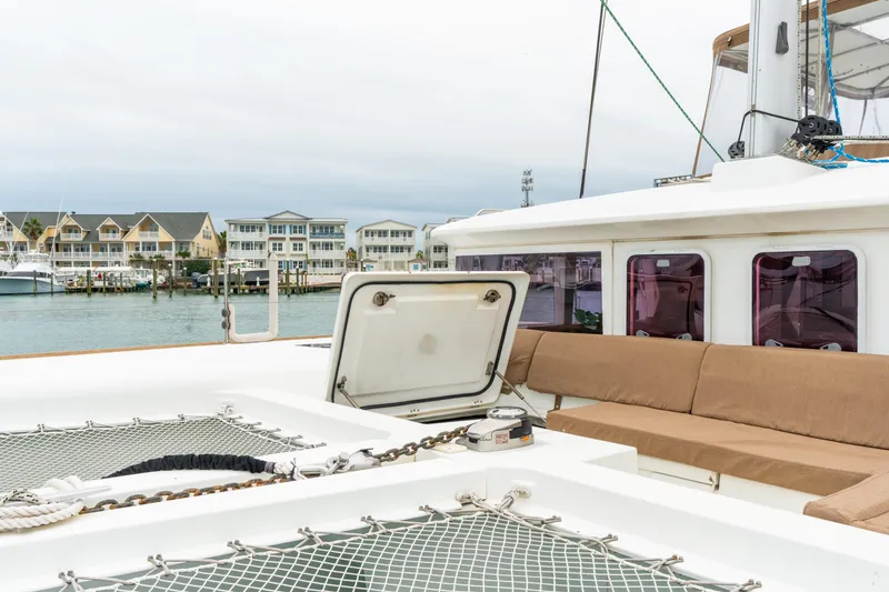 Slide: The Image of 2013 Lagoon 450 catamaran with open hatch, docked near waterfront homes. - 85