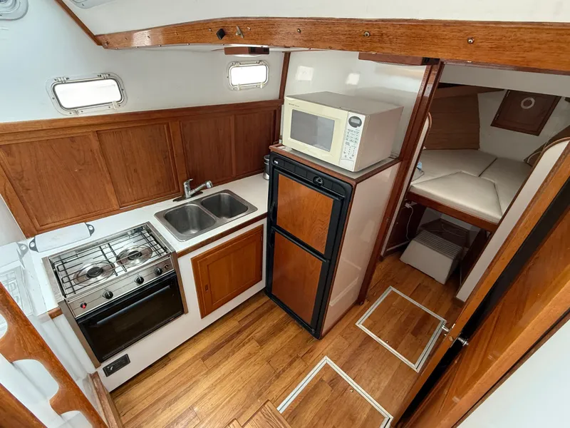 Slide: The Image of 1998 Wilbur 38 Downeast boat interior with kitchen, stove, sink, fridge, and microwave. - 19
