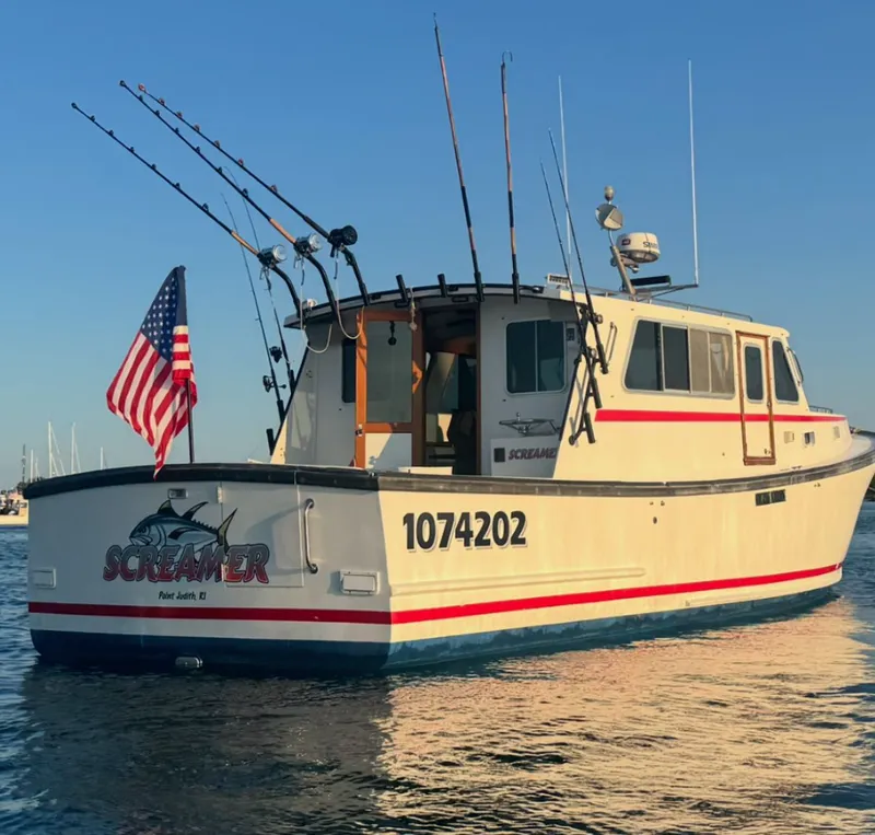 Slide: The Image of Wilbur 38 Downeast 1998 boat with fishing rods and American flag on calm water. - 2