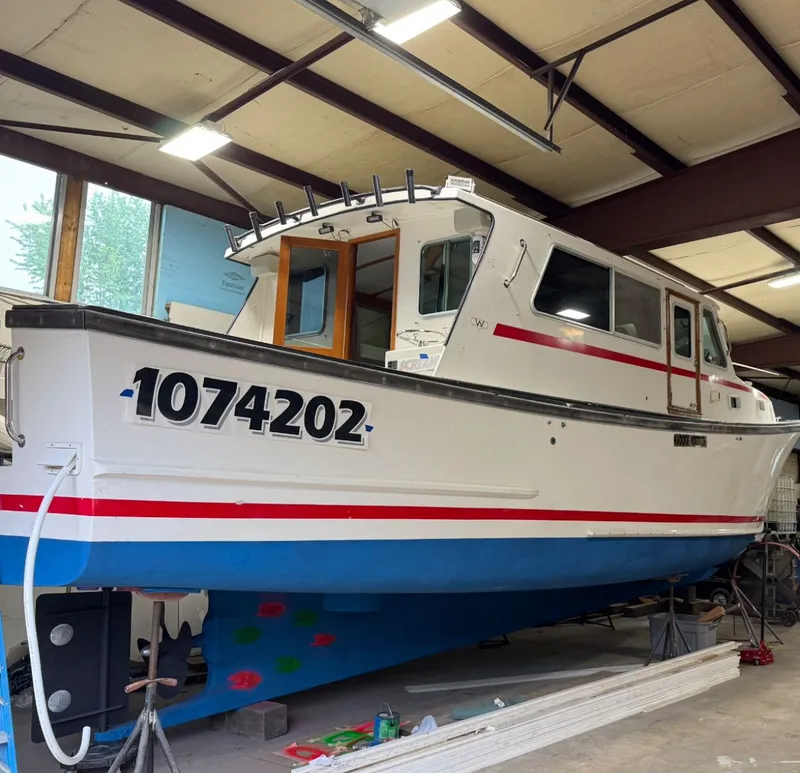 Slide: The Image of 1998 Wilbur 38 Downeast boat in a workshop, white with red and blue accents. - 6