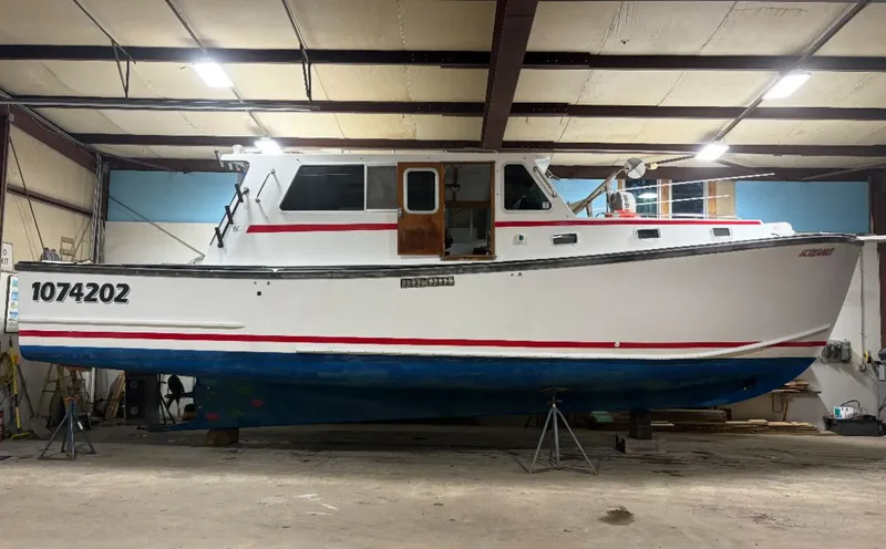 Slide: The Image of 1998 Wilbur 38 Downeast boat in a warehouse, white with red and blue accents. - 7