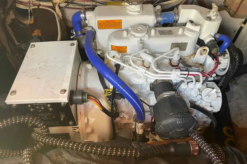 Slide: The Image of Engine compartment of a 1989 Island Packet 35 sailboat, featuring blue hoses and wiring. - 10