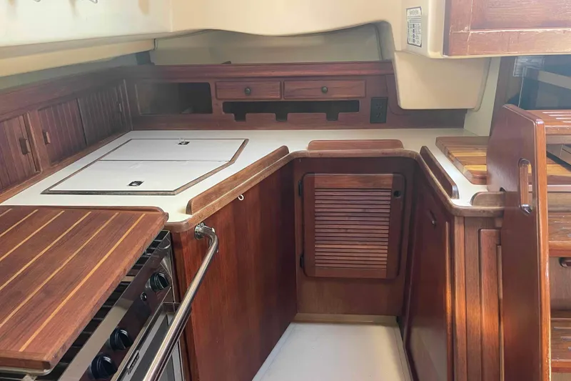 Slide: The Image of 1989 Island Packet 35 yacht kitchen with wooden cabinetry and modern appliances. - 17