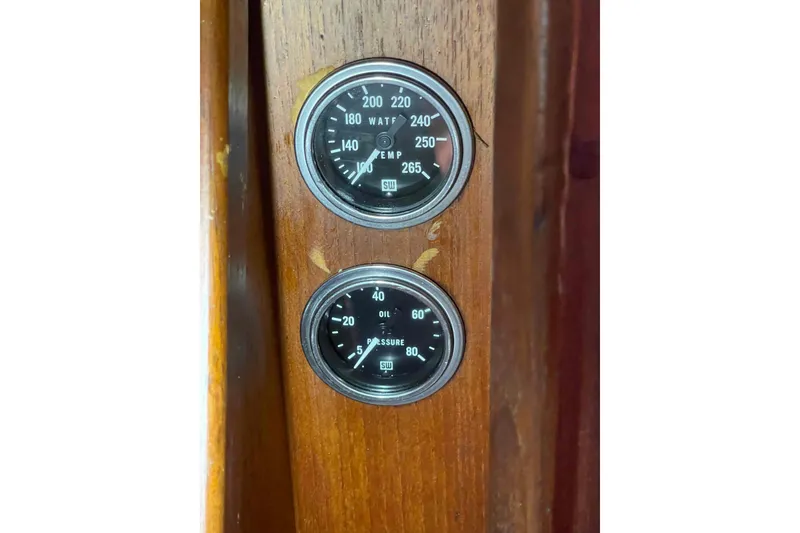 Slide: The Image of 1989 Island Packet 35 boat gauges on wooden panel, displaying temperature and oil pressure. - 33